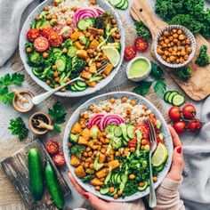 two bowls filled with chickpeas, cucumber, tomatoes and broccoli