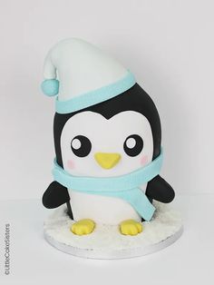 a penguin wearing a hat and scarf on top of a white surface with a light blue ribbon around its neck