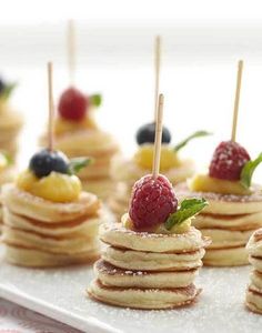 small pancakes with fruit on top and toothpicks sticking out of the stacks are ready to be eaten