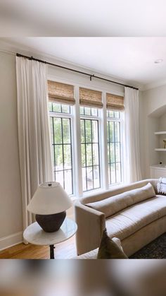 a living room filled with furniture and lots of white curtains on the window sill