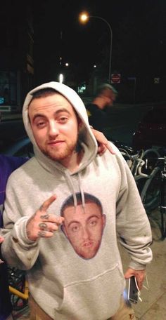 two men standing next to each other in front of parked bikes and one is wearing a hoodie