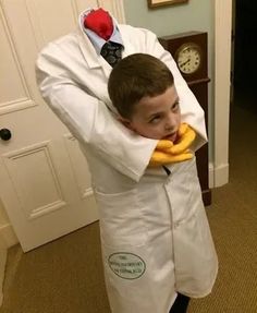 a young boy dressed as a doctor holding a banana in his hands and wearing a white lab coat