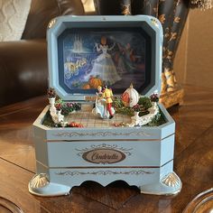 an ornate blue box with figurines in it on top of a wooden table