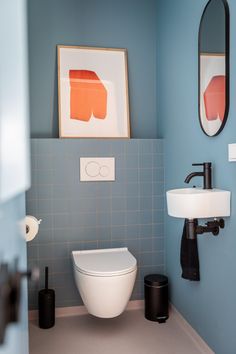 a bathroom with blue walls and white fixtures, including a toilet in the corner next to a sink