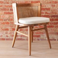 a wooden chair with a white cushion on top of it next to a brick wall