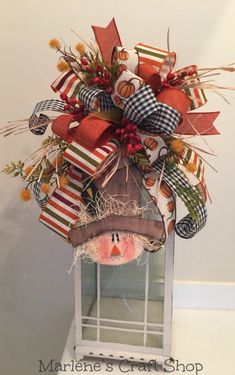 a scarecrow decoration hanging from the side of a window with hay and pumpkins on it