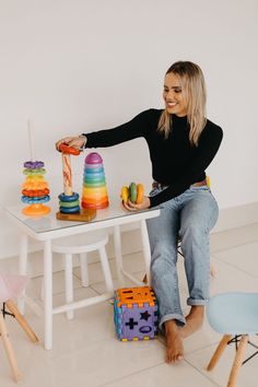 a woman sitting at a table with some toys on top of it and an object in front of her