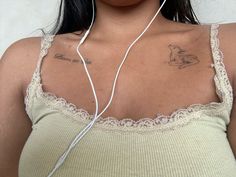 a woman with ear buds and a tattoo on her chest