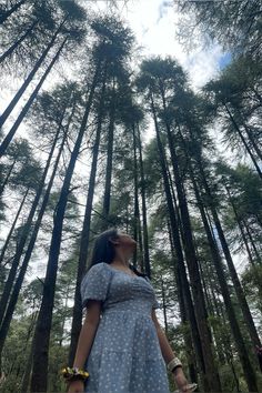 a woman standing in front of tall pine trees