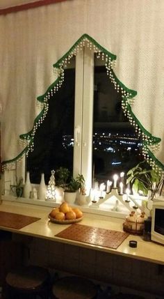 a decorated christmas tree sitting on top of a kitchen counter next to a large window