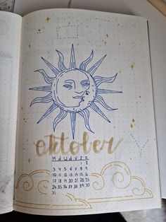 an open notebook with the sun and moon drawn on it's cover in gold ink