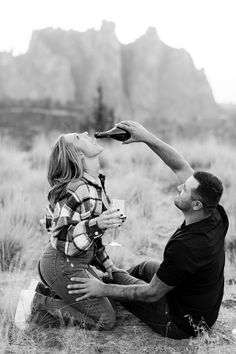 a man and woman sitting on the ground drinking water