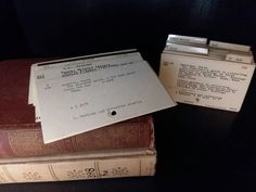 two old books stacked on top of each other with paper attached to the back covers