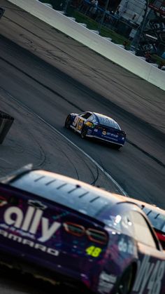 two cars racing on a race track during the day