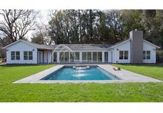 a house with a pool in front of it and grass around the pool area on both sides