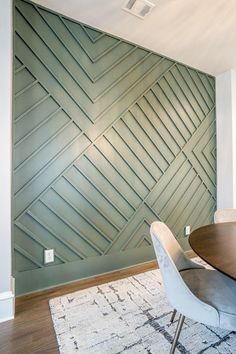 a dining room table and chairs in front of a green wall with wavy lines on it