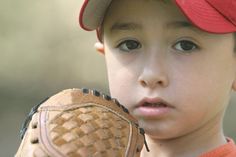 a young boy wearing a catchers mitt looking at the camera