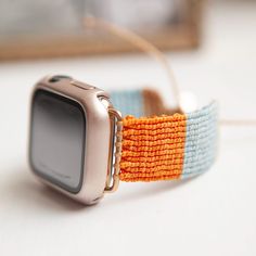 an orange and blue watch band with a silver apple watch on it's side