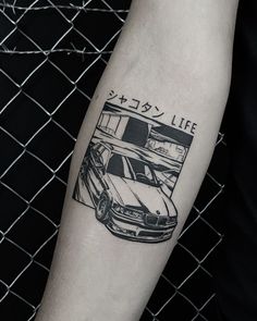 a black and white photo of a car tattoo on the left arm with japanese writing