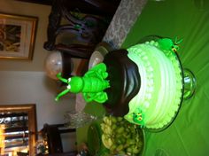 a green and black cake sitting on top of a table next to other food items