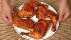 a person holding a plate with chicken wings on it