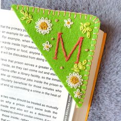 an open book with flowers and the letter m on it