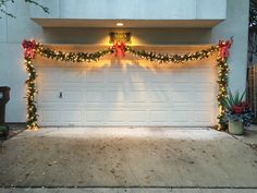 a garage decorated for christmas with lights and garland on the front door is lit up