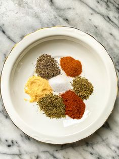 a white plate topped with spices on top of a marble counter next to a knife and fork