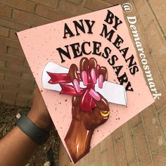 someone holding up a pink graduation cap that says, any means necessary