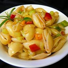 a white bowl filled with pasta and veggies on top of a black table