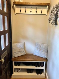 a wooden bench sitting next to a door with shoes on it's shelf and coat rack