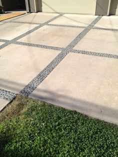 a driveway with grass and a garage door in the background