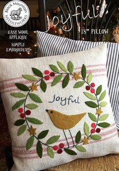 two pillows on a chair with the words joyful written in it and an embroidered bird