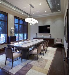 a large dining room table with chairs and a flat screen tv mounted on the wall