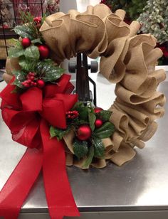 two christmas wreaths with red bows on top of a metal counter next to each other