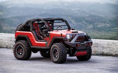 a red and black jeep parked on top of a hill