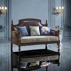 a couch with many pillows on it in front of a blue wall and chandelier