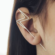 a woman's ear is shown with a pair of earrings in the shape of a lightning bolt