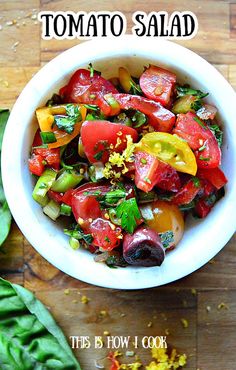 a white bowl filled with tomato salad on top of a wooden table