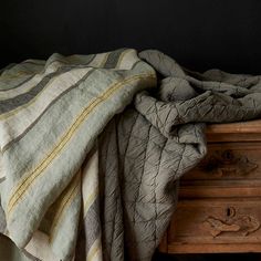 an unmade bed with a blanket on top of it next to a wooden dresser