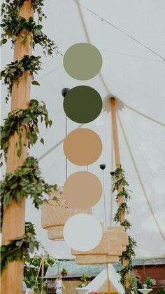 an outdoor wedding with greenery hanging from the ceiling and large circular chandelier