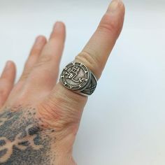 a man's hand with a ring on it that has an emblem on it