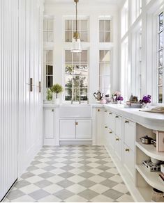 a white kitchen with checkered flooring and lots of window sill on the side