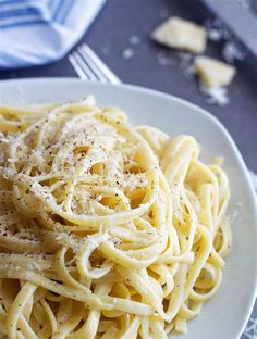 a plate of pasta with parmesan cheese on the top and fork next to it