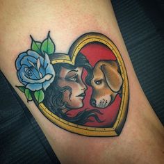 a woman with a dog in a heart tattoo on her leg, next to a blue rose