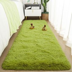 two rabbits are laying on a green rug in the middle of a bedroom with white walls