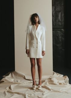 a woman standing in front of a white backdrop wearing a wedding dress and veil with her hands on her hips