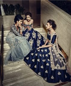 three women in blue dresses sitting on stairs