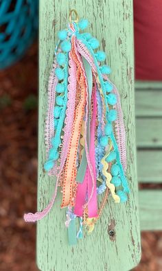 a bunch of colorful bracelets hanging from a wooden pole in front of a potted plant