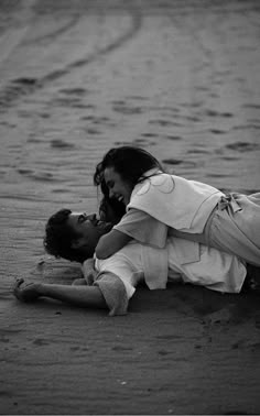 a man and woman are laying on the ground in black and white, with their heads touching each other